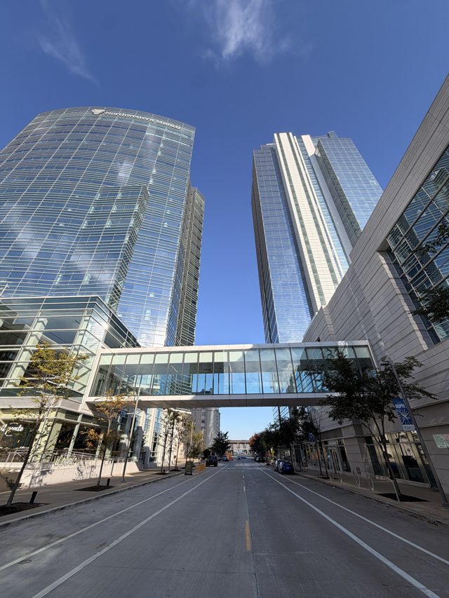 Two glass towers joined by a skybridge over an empty street.