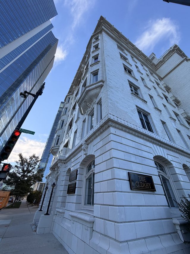 The Cudahy, a white stone apartment tower, shot from the corner looking straight up, a glass tower behind it.