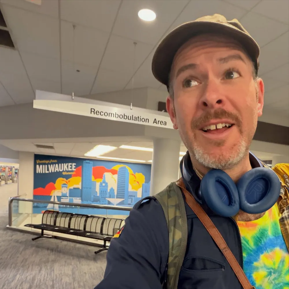 Aaron in a tie-dye shirt and headphones at the Milwaukee airport
