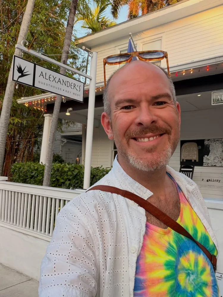 Aaron grinning under the Alexander's Guesthouse sign