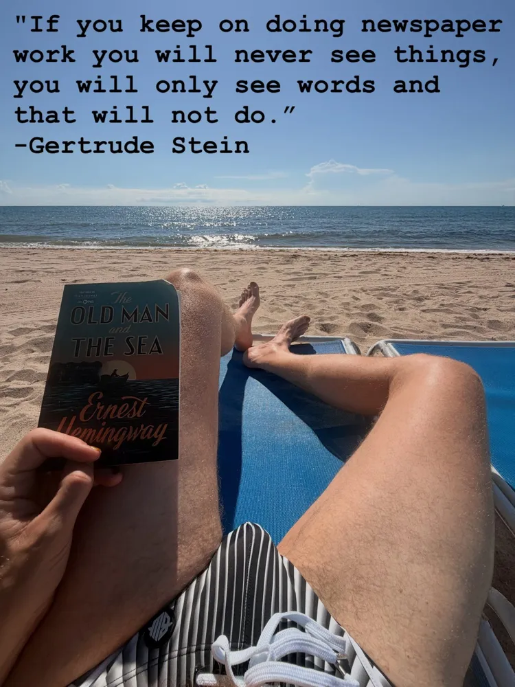 Aaron's legs on a beach chair, Old Man and the Sea in hand, a Gertrude Stein quote over the ocean