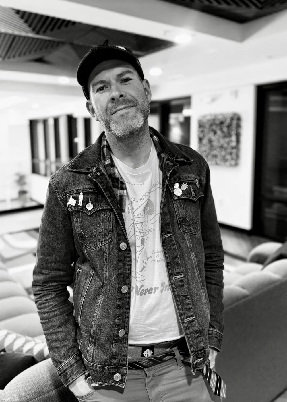 Aaron Berth in black and white, in a cap and denim jacket, hands in his pockets