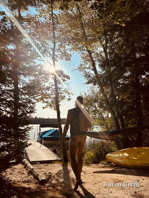 Aaron from behind, backlit by the sun, walking toward a dock in a jockstrap