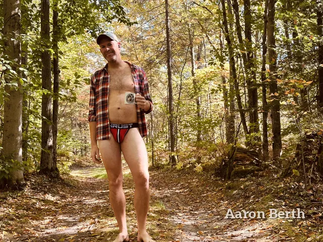 Aaron on a forest road in a cap, an open plaid shirt and red briefs