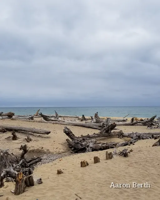 A driftwood teepee on a Lake Superior beach under heavy clouds