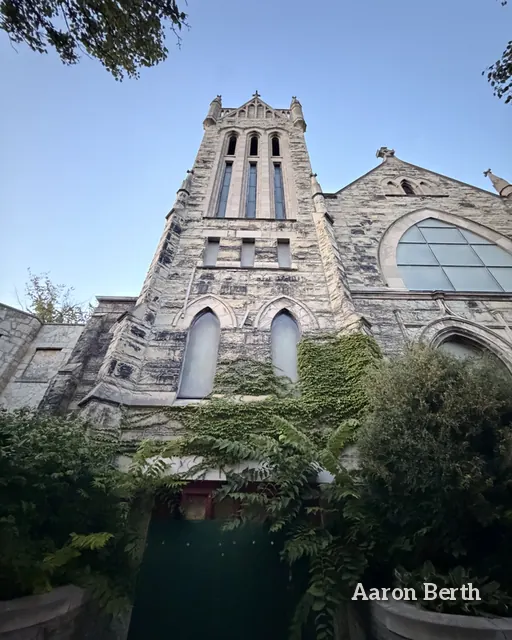 A gothic stone church tower seen from below against blue sky