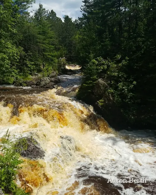 Amnicon Falls rushing brown over rock between green banks