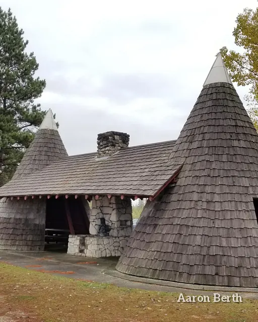 A cone-roofed wood shingle shelter in a pine grove