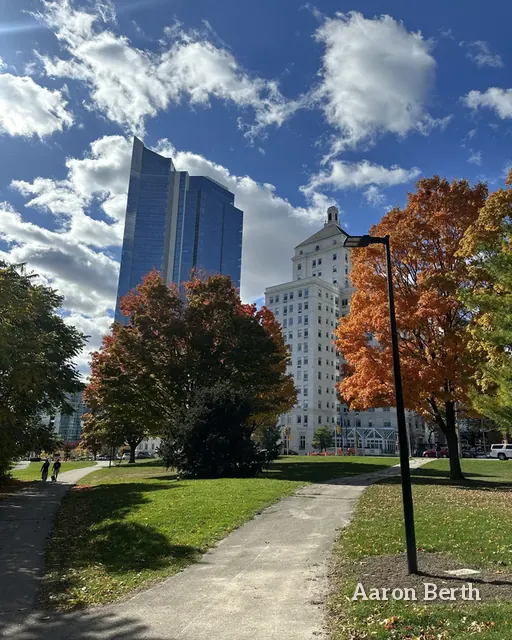 Downtown Milwaukee towers over a footpath and orange fall trees