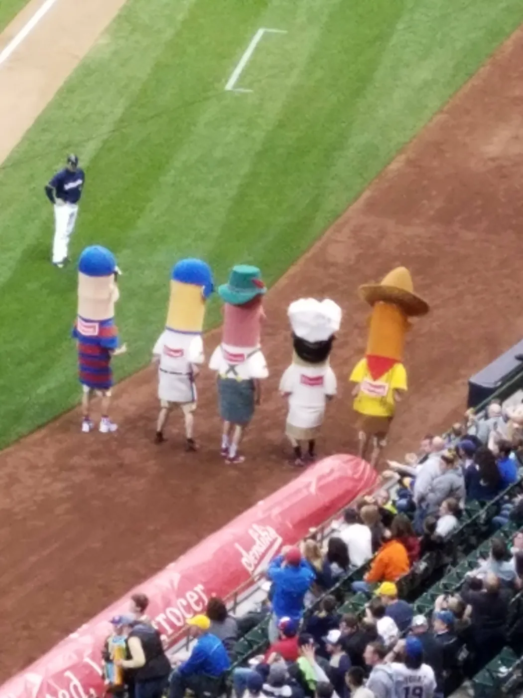 The racing sausage mascots lined up on the warning track