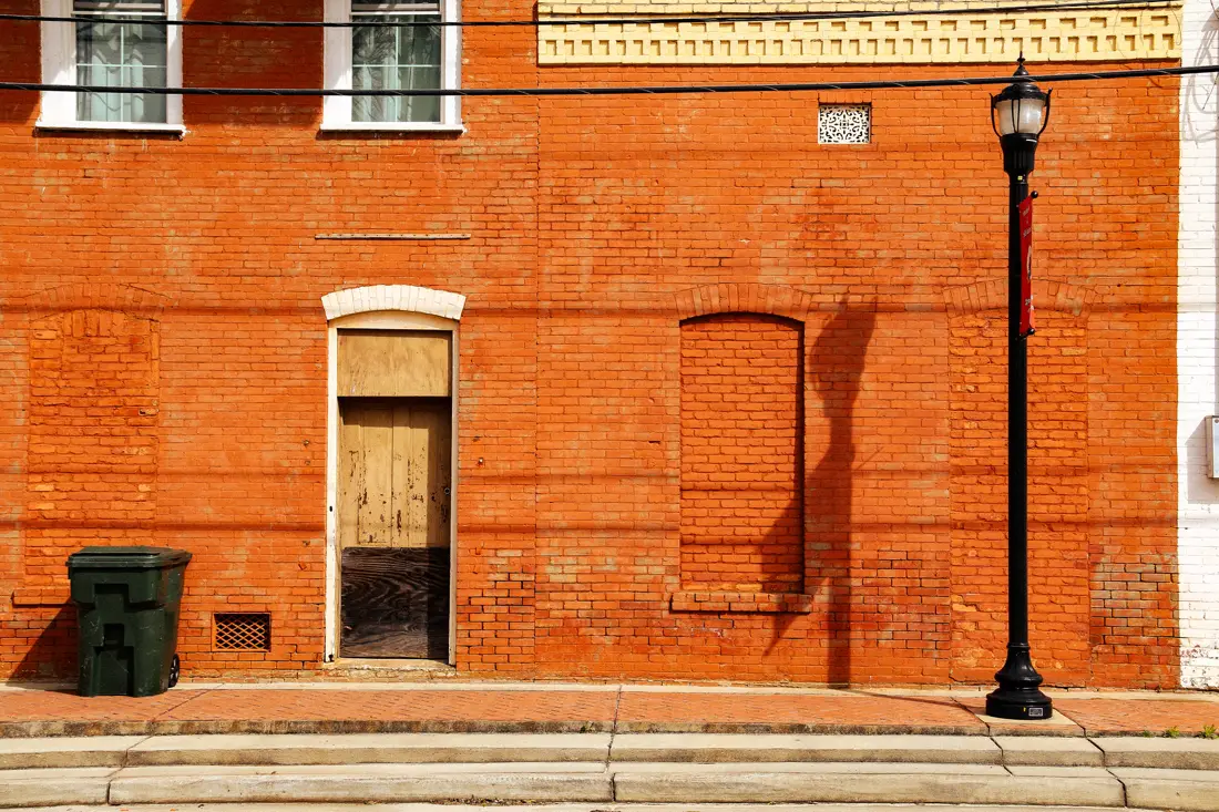 A red brick storefront and a street lamp on a small-town corner