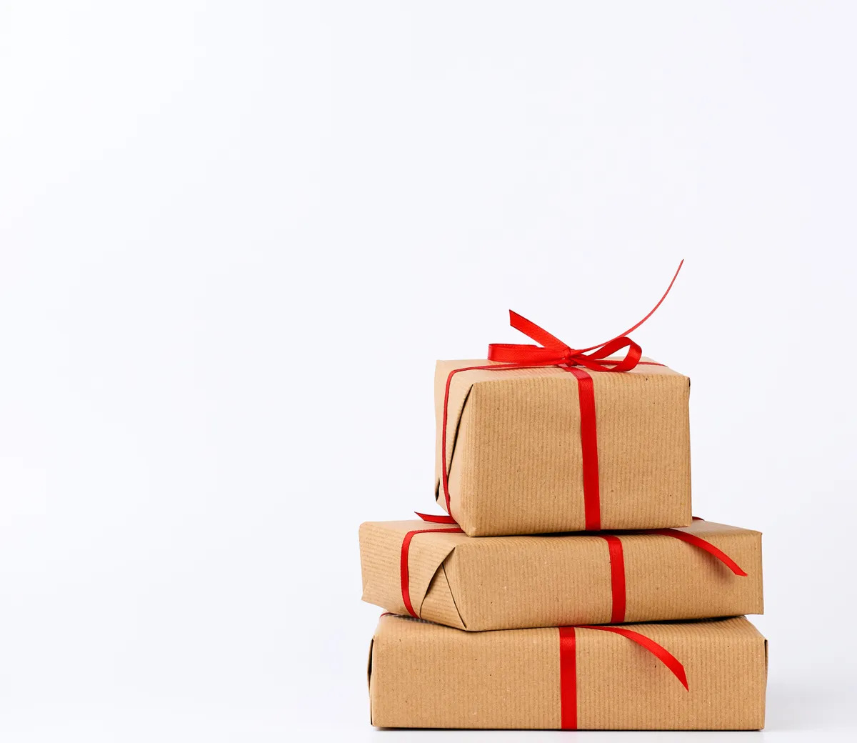 A stack of gifts in kraft paper tied with red ribbon